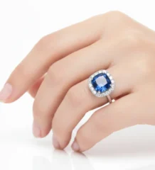 Blue sapphire halo ring with diamond surround on finger